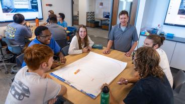 Table of students talks to professor during Design I