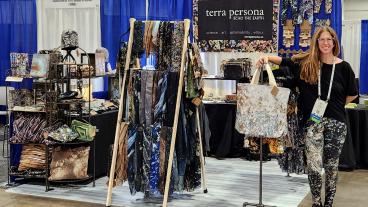 Teresa Johnson poses with Terra Persona booth at trade show