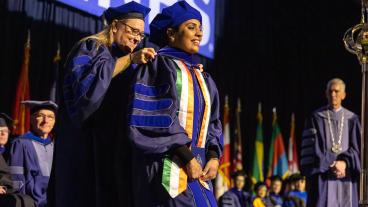 PhD graduate during hooding ceremony at 2022 midyear commencement