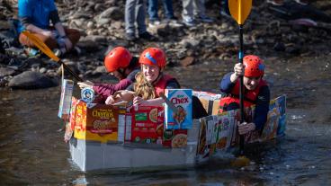 Students paddle down creek in cardboard boat
