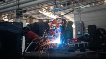 Person in welding shield welding with sparks flying