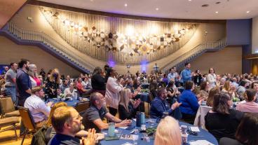 People standing and applauding in campus event hall