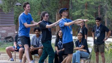 three students with hands on shoulders performing skit