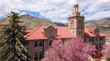 Guggenheim Hall with blooming trees against backdrop of Mount Zion and blue sky