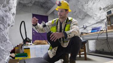 PhD student in safety gear in an underground mine chamber working on a scintillator