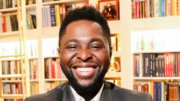 headshot of john akinboyewa in front of books