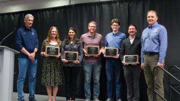 five faculty members standing on stage holding awards