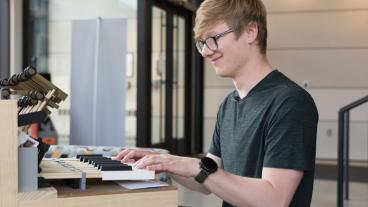male student with hands on keyboard of new instrument