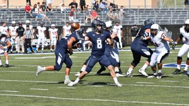 Justin Dvorak gets ready to throw a football surrounded by other football players during a Mines football game