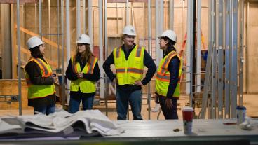 four students in construction gear in building site 