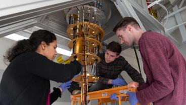 A faculty member and two students work on a dilution refrigerator in a quantum lab on the Mines campus