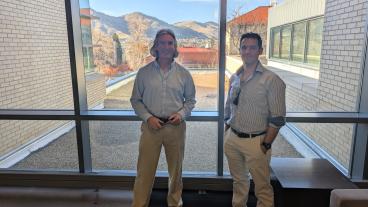 Mark Deinert and Andy Osborne stand in front of window with Mines campus behind