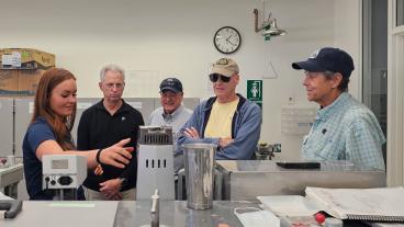 four male alumni get lab tour from female student