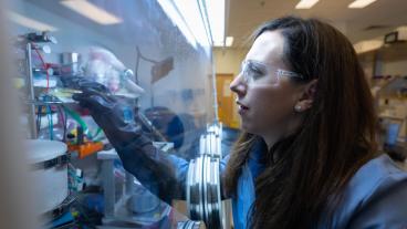 female researcher in safety glasses works in fume hood