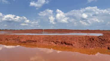 red mud tailings with clouds reflected in water