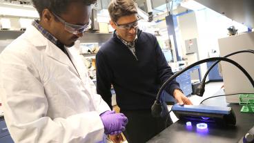 Henok Yemam, PhD candidate in applied chemistry, and Chemistry Associate Professor Alan Sellinger demonstrate the behavior of scintillators under UV light.