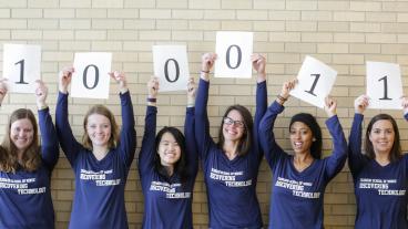 Students holding up binary number signs