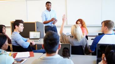 Stock image of students and teacher engaged in classroom discussion