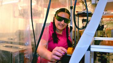 Alyssa Allende Motz inspects a machine in an engineering physics lab