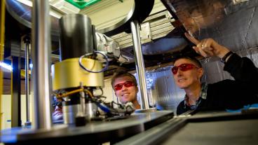 Lawrence Wiencke and a male student inspect machinery in a physics lab.