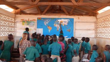Ghanaian students point to a map on a classroom wall