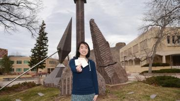 Emily Wong, creator of Project Positivity, in front of “The Greeting” on Kafadar Commons.