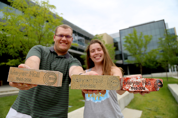 David Schmidt and Lindsey Hart holding Meyer Hall bricks